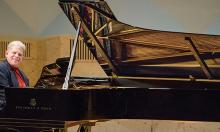 Dick Forman sitting at a grand piano on stage