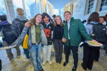 Student presenters celebrate after completing their session. Four people smiling at the camera in busy hallway.