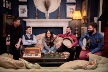 the artists sitting on a sofa with their instruments