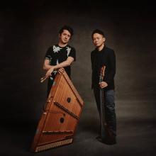 the two artists standing next to each other holding their instruments