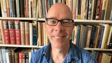 Ian Barrow smiling in front of bookshelves