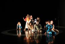 a group of dancers, some sitting and some standing, against a black background