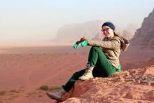Photo of a student sitting on a rock outcrop, overlooking the desert of Wadi Rum.