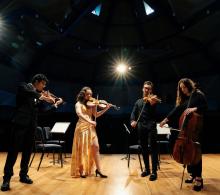 Members of the quartet standing on stage with their instruments