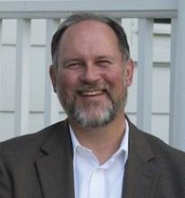 smiling bearded white man wearing white button-down shirt and brown sport jacket