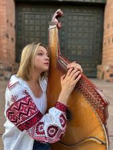 Krut standing outside holding an instrument