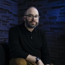 The artist seated against a dark background