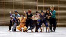 Dancers with arms linked, in a line.