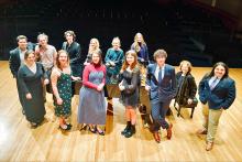 group of students standing on the stage with their accompanist
