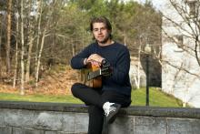 the artist seated and holding a guitar