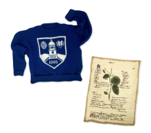 blue knit sweater with middlebury shielf and embroidered textile rectangle resembling a sheet of paper