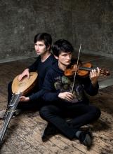 two artists sitting on the floor holding their instruments