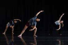 3 dancers dancing against a black background