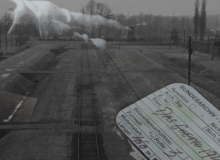 Black and white photograph of a concentration camp with smoke drifting across.