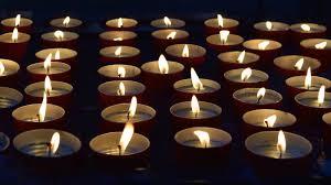 Image of lit candles lined up in rows