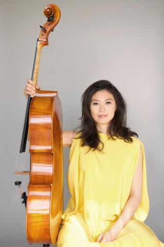 artist in a yellow dress holding the cello