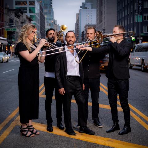 5 people standing on a street holding their instruments