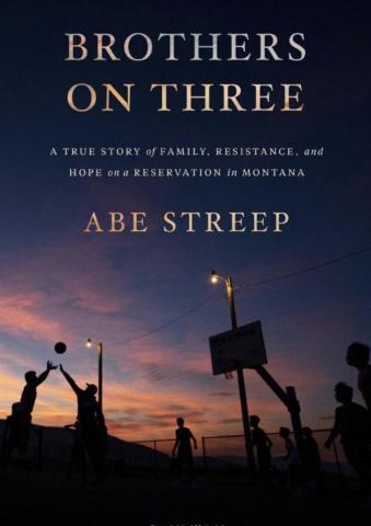 Book cover of 'Brothers on Three' by Abe Streep. Text reads: 'A true story of family, resistance, and hope on a reservation in Montana.' Background is a photograph of a group of people playing basketball, silhouetted against a dusk sky.