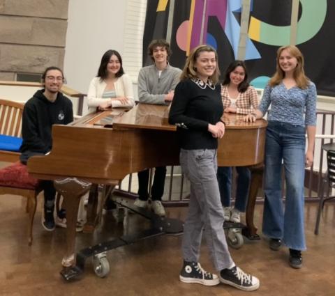 student perfomers standing around a piano