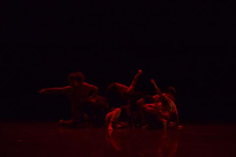 Dancers against a black background with red lighting