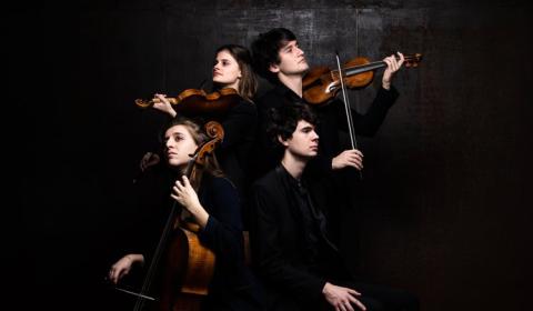 The quartet with their instruments in front of a black background