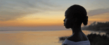 Woman looking across a body of water at sunset