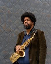 photo of the artist holding a saxophone