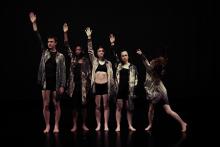 dancers standing in a line against a black background