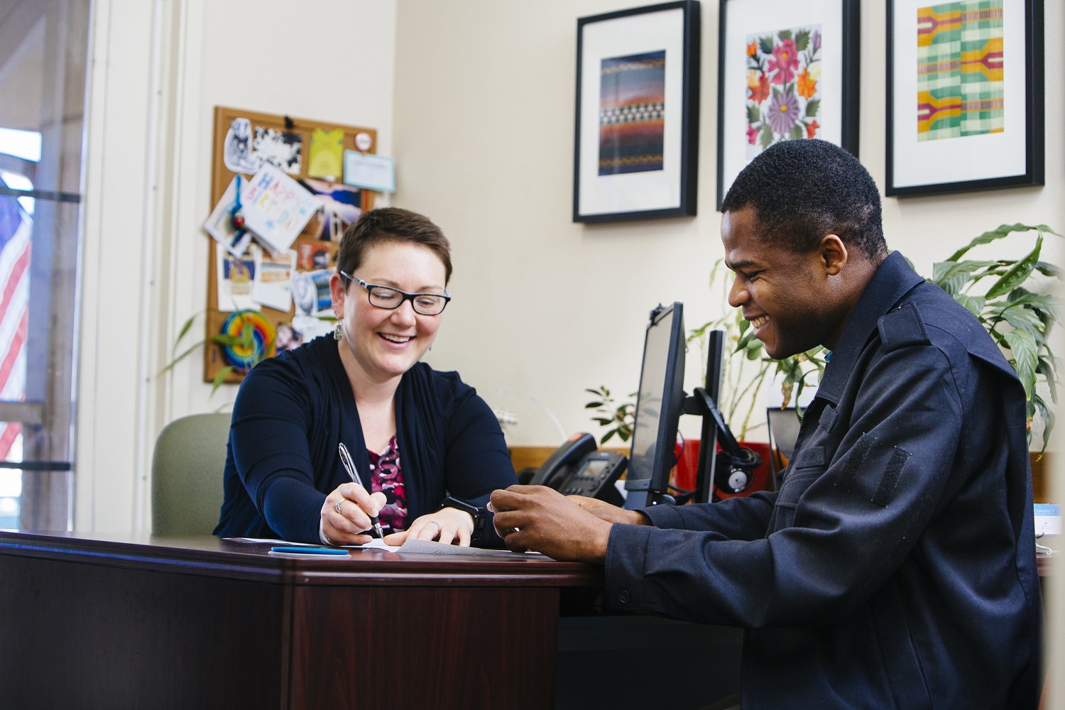 Smiling student sitting across a table from his advisor as she writes