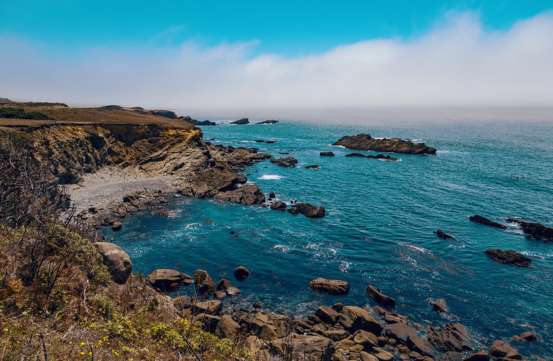 Salt Point State Park, golden cliffs and turquoise waters against a blue sky with white coastal clouds