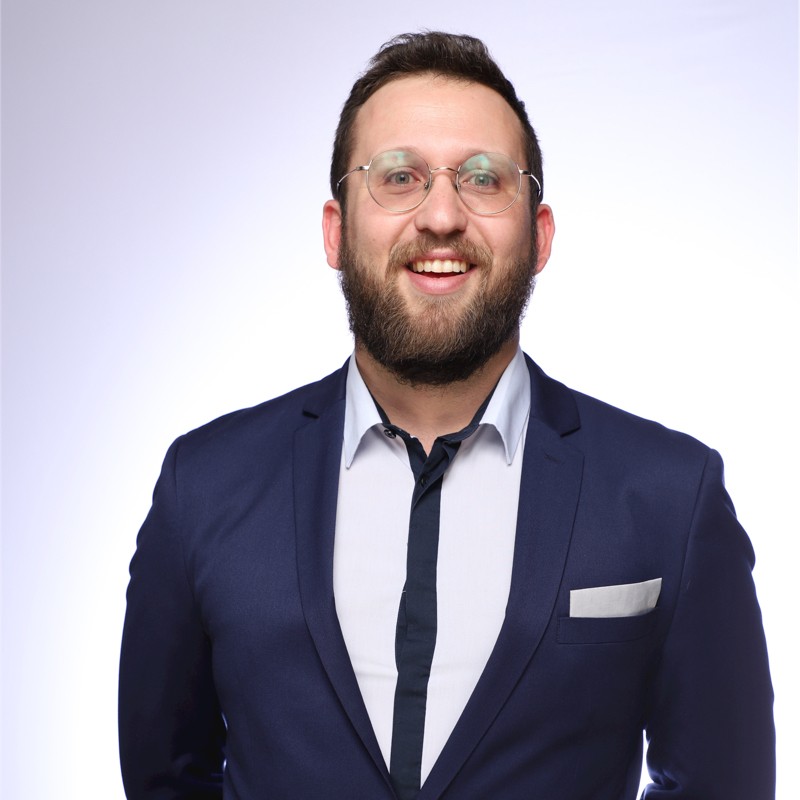 Mr. Nico De Golia in a blue blazer, with a broad smile, beard, and glasses.  He looks like a go-getter, and he is. 