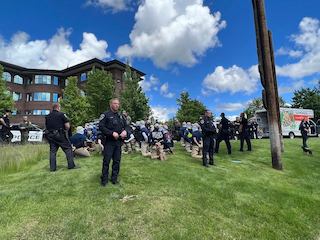 Police stand guard around a group of militia men on their knees. A u-Haul is seen in the background