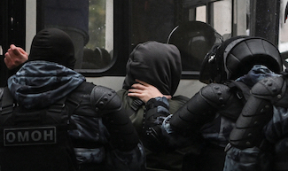 A protestor is pinned against a vehicle by Russian security personnel