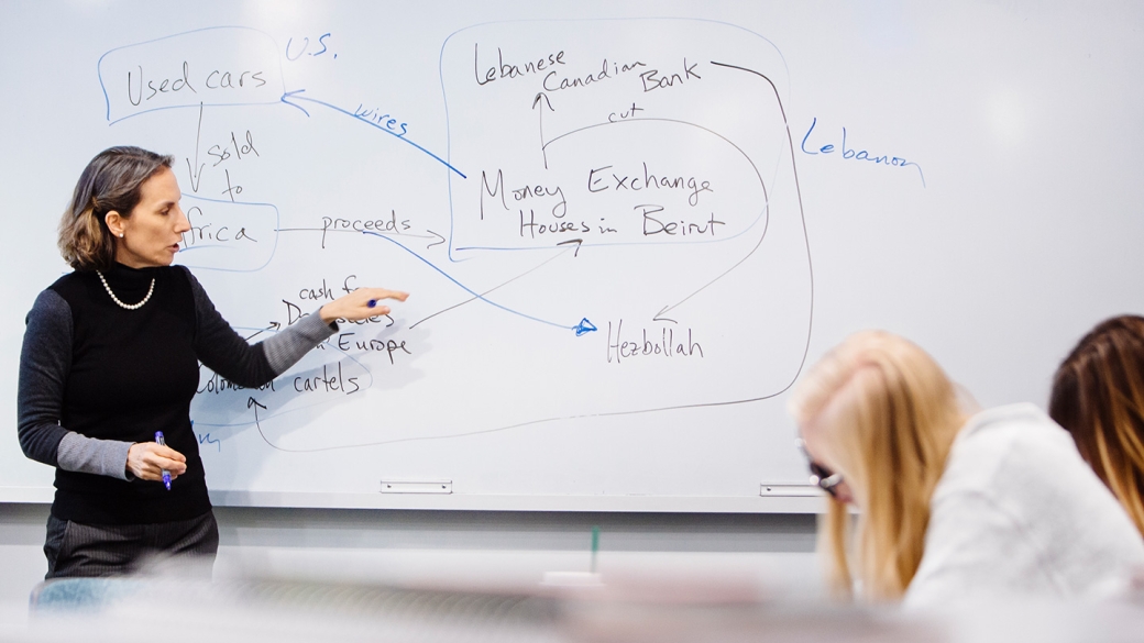 Professor in front of whiteboard showing terrorism financing analysis