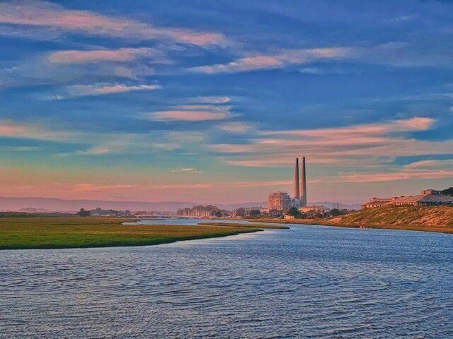 Image of Moss Landing (now retired) power plant at Elkhorn Slough--a big sky above with pastel colors, big water below as the slough spread out
