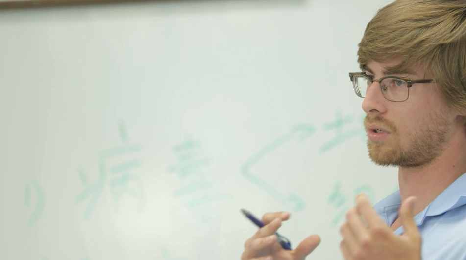 Student in front of whiteboard featuring Chinese characters