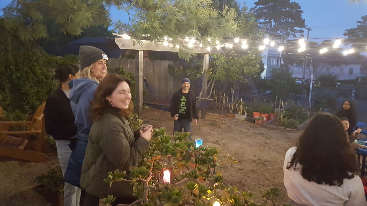 lights in the garden at dusk, people standing, drinking