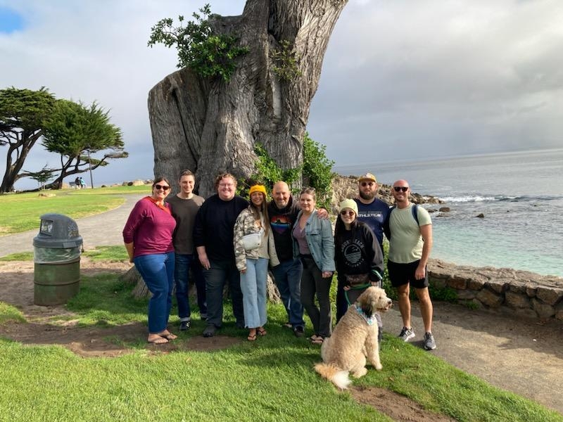 a group of people standing by a massive cypress tree at Lover's Point, in Pacific Grove, CA