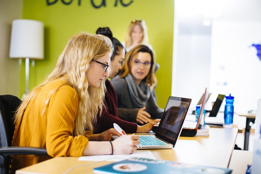 Student working at her computer with other students in the background