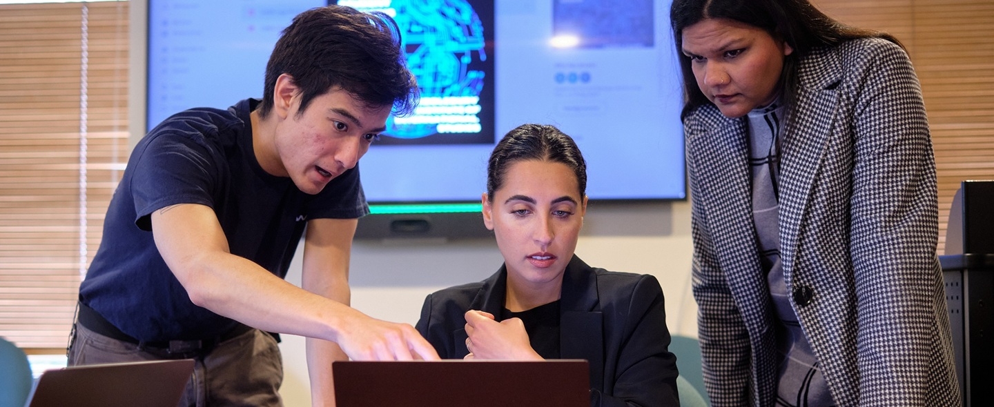 Three students looking at a computer