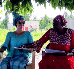 Spencer Chappell in Senegal sitting outside with a coworker doing paperwork