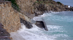 Ocean splashing and covering steps leading to the beach