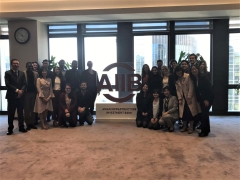 Group of students and professors standing around a sign for the Asian Infrastructure Investment Bank. The sign is red. 