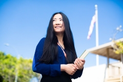 Well-dressed student, Nuan He, holds a book and looks off into the distance