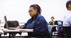 Student reflecting with her laptop open during a class 