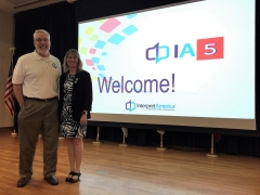 Barry Olsen and Katherine Allen standing side by side on a stage in front of a digital screen