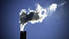 Smokestacks at a power plant in Arizona, black stacks with white smoke against a moody blue dark sky