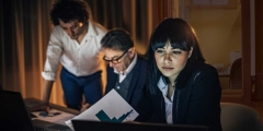 Woman reviews materials with colleagues in background doing same