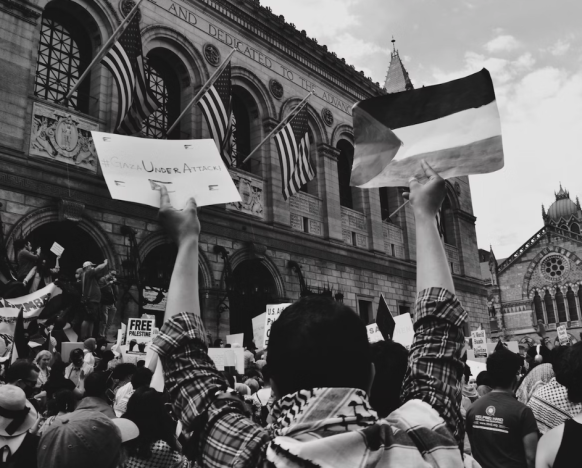 Large crowd in protest, hands in the air with protest signs and flags