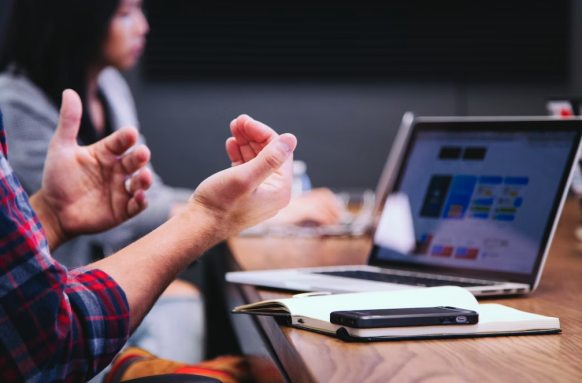 Hands in front of computer screen as if in conversation